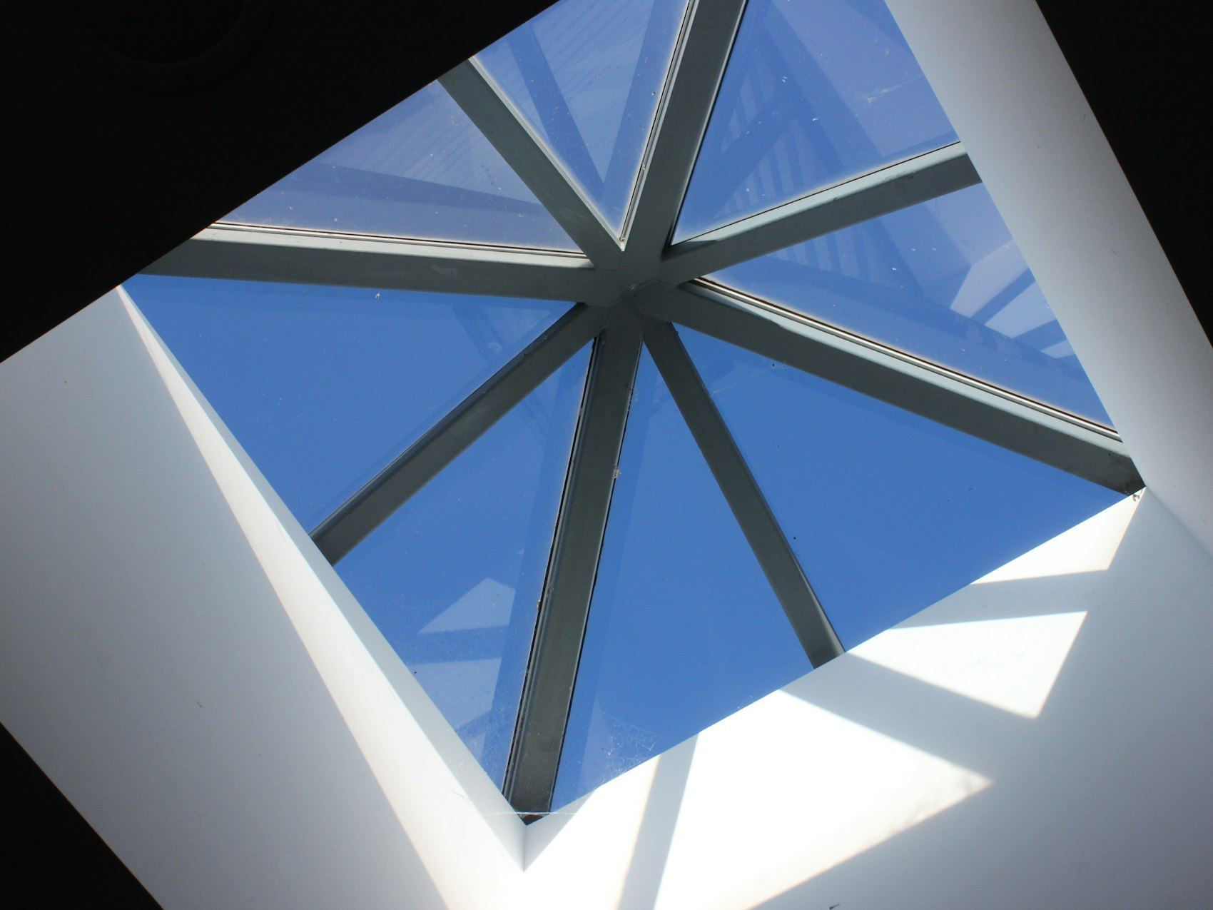 Geometric skylight frame viewed against a clear blue sky.