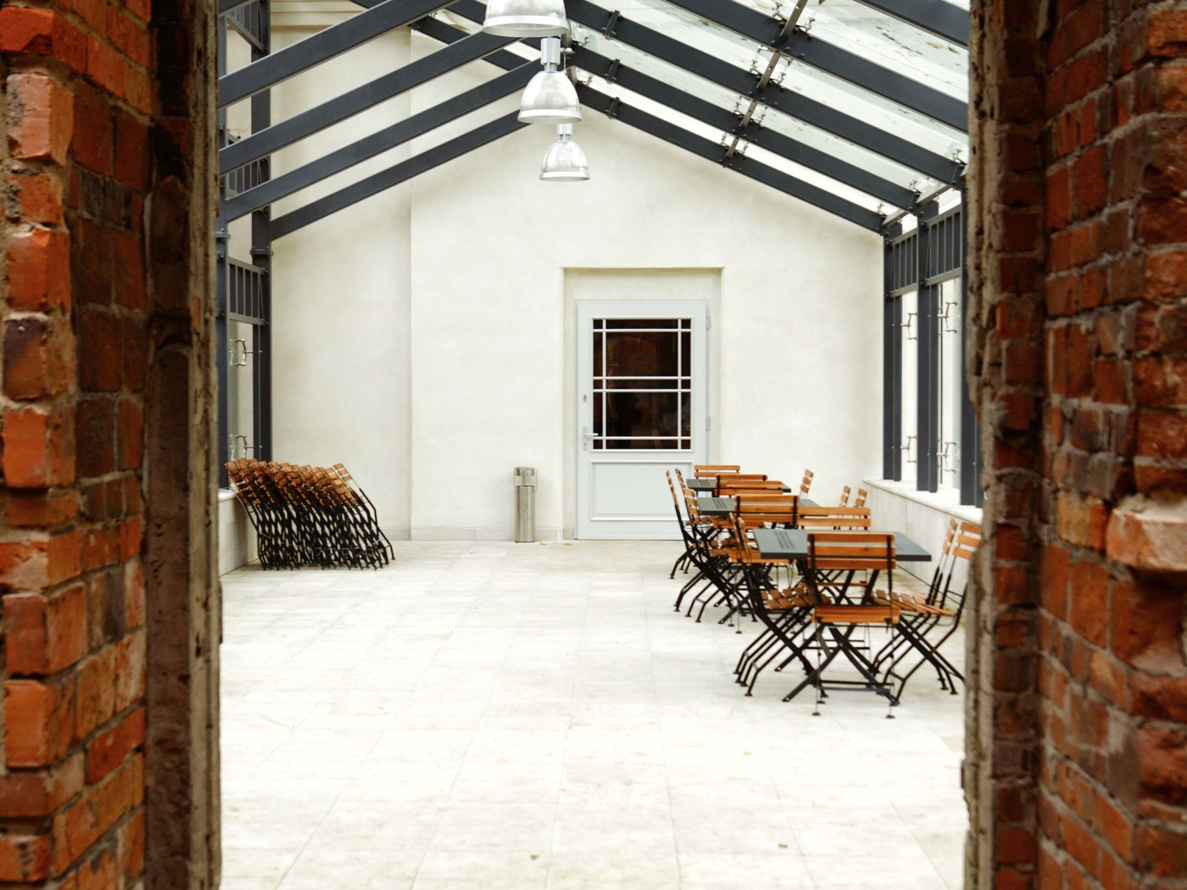 Indoor dining area with wooden tables seen through a brick archway.