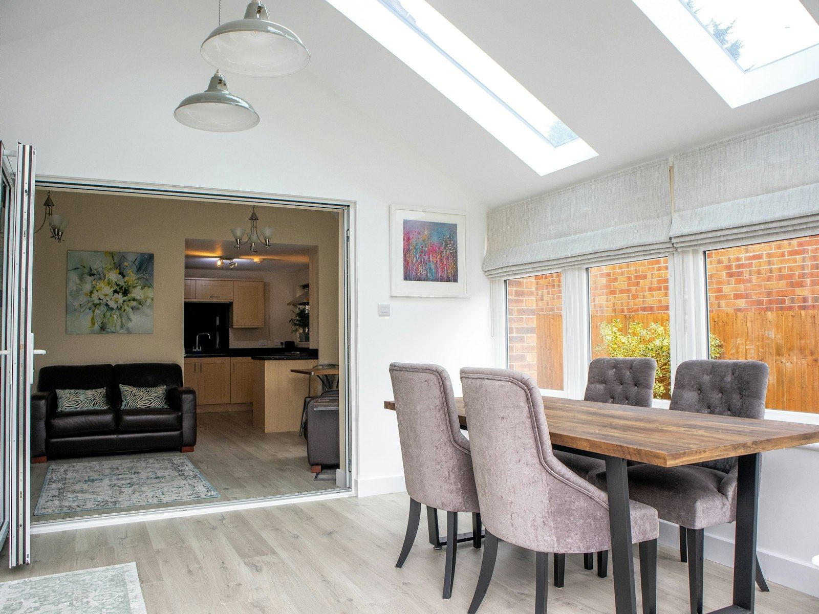 Bright dining room extension with skylights leading to a kitchen.
